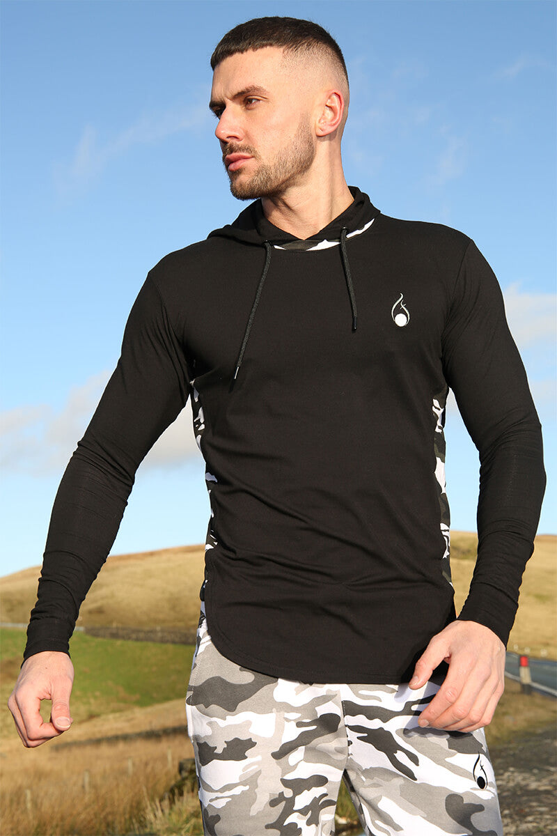 A man wearing a Prestige Camo Hooded Tee – Black with camouflage side panels, paired with matching shorts.